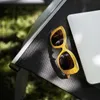 A close-up shot of sunglasses and a laptop on a black outdoor chair. Produktbild-Vorschau