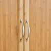 A close-up view of two silver cabinet handles on a wooden surface. Produktbild-Vorschau