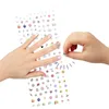 A child's hands are shown applying stickers to fingernails from a sheet of stickers. Anteprima dell’immagine prodotto