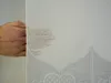 A hand is shown holding a sheer white curtain with embroidered details. Produktbild-Vorschau