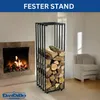 A modern black metal firewood rack filled with logs stands next to a stone fireplace with a fire burning. A neutral-colored armchair is visible in the background. Produktbild-Vorschau
