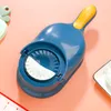 A blue and yellow dumpling maker is shown on a pink background. Podgląd zdjęcia produktu