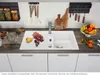 A kitchen sink area with fruit and utensils, suggesting food preparation. Produktbild-Vorschau