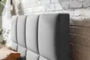 Close-up of a padded headboard next to a brick wall. Náhled obrázku produktu