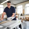 A man is using a table saw in a workshop. Podgląd zdjęcia produktu
