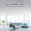 A modern living room with large windows, a sectional sofa, and a ceiling light. Produktbild-Vorschau