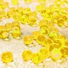 A close-up shot of many small, translucent yellow gel beads scattered on a sparkly gold surface. Produktbild-Vorschau