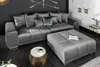 A modern living room with a large gray sectional sofa and a matching ottoman. Produktbild-Vorschau
