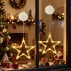 Christmas decorations in a window, including lit star ornaments, a Christmas tree, and a Santa figure. Produktbild-Vorschau