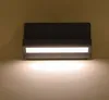 A dark gray outdoor wall light with a white LED light strip, mounted on a light brown wall. Produktbild-Vorschau