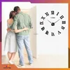 A couple embracing in front of an open door, with a large wall clock on the adjacent wall. Náhled obrázku produktu