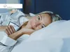 A woman is lying in bed, smiling at the camera. Produktbild-Vorschau