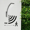 A wall-mounted LED lamp with a motion sensor is shown next to a green hedge. Graphics indicate the motion sensor's range. Náhled obrázku produktu