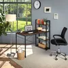 A home office setup with a computer desk, chair, and shelving unit next to a large window. Produktbild-Vorschau