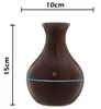 A dark brown aroma diffuser with a blue light ring, shown against a white background with dimensions indicated. Produktbild-Vorschau