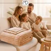 A family is sitting on a couch with a blanket in the foreground. Anteprima dell’immagine prodotto