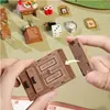 Hands assembling a miniature wooden furniture piece, with other miniature items in the background. Podgląd zdjęcia produktu