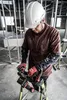 A construction worker wearing a hard hat and gloves is working on a ladder with tools. Podgląd zdjęcia produktu