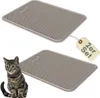 Two gray cat litter mats are shown, with one mat having a tag attached. A tabby cat is sitting in the foreground next to the bottom mat. Produktbild-Vorschau