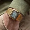 A close-up shot of a person's wrist wearing a gold digital watch. Produktbild-Vorschau