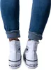 A rear view of a person wearing white Converse Chuck Taylor All Star high-top sneakers and blue jeans. Anteprima dell’immagine prodotto
