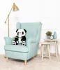 A plush panda toy sits on a light blue armchair next to a small side table with decorative items. Anteprima dell’immagine prodotto