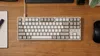 A top-down view of a mechanical keyboard on a wooden desk. Produktbild-Vorschau