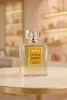 A perfume bottle is displayed on a white table with a blurred background of shelves filled with products. Produktbild-Vorschau