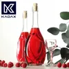 Two glass bottles filled with red liquid, a small glass, and raspberries are arranged on a surface with a sprig of eucalyptus in the background. Voir les images du produit