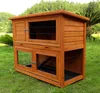 A wooden rabbit hutch with multiple levels is shown outdoors on a grassy lawn. Produktbild-Vorschau