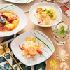 A table setting with multiple plates of food and a glass of water. Náhled obrázku produktu