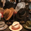 A collection of various hats displayed on a dark wooden surface. Produktbild-Vorschau