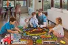 A family is playing a board game on the floor in a living room. Voir les images du produit