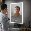 A man in a bathrobe is looking into a lighted mirror in a bathroom. Podgląd zdjęcia produktu