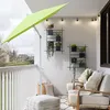 A balcony setup with a green umbrella, seating, plants, and decorative elements. Produktbild-Vorschau