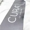 A close-up of a woven label attached to a white textile product. Podgląd zdjęcia produktu