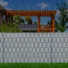 A fence made of grey PVC privacy strips in a garden setting with rain falling. Produktbild-Vorschau