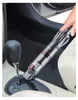 A hand is using a handheld vacuum cleaner to clean the interior of a car, near the gear shift. Produktbild-Vorschau