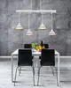 A dining table with chairs and a chandelier in a room with a concrete wall. Náhled obrázku produktu