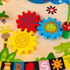 A close-up view of a colorful wooden activity table for children, featuring gears and animal illustrations. Podgląd zdjęcia produktu