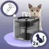 A cat is looking at an automatic pet water fountain. The fountain is on a light purple platform. There are inset images showing a part of the fountain and a silhouette of a cat with '2x'. Produktbild-Vorschau