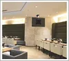 A modern dining or lounge area with upholstered seating, tables, and a ceiling-mounted TV. Produktbild-Vorschau