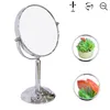 A silver makeup mirror on a stand, with inset images showing a succulent plant and sliced fruit. Produktbild-Vorschau