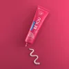 A pink tube of Curaprox toothpaste with a swirl of toothpaste on a pink background. Náhled obrázku produktu