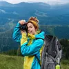 A woman is taking a photo with a camera in a mountainous landscape. Náhľad obrázku produktu