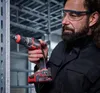 A man wearing safety glasses and earplugs is using a cordless drywall screw gun to attach a metal stud to a wall. Voir les images du produit