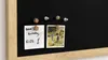 A close-up shot of a magnetic chalkboard in a house shape, with a wooden frame, displaying a handwritten note and a photograph attached with magnets. Produktbild-Vorschau