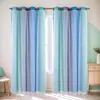 Two blue and teal gradient sheer curtains with white dots, hanging from a curtain rod in front of a window. A small wooden chair with a teal cushion is visible on the left, and a wooden cabinet with a white vase is on the right. Voir les images du produit