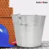 A metal bucket, a blue hard hat, and red object are placed next to a stack of bricks. Náhled obrázku produktu