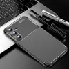 A smartphone case with a carbon fiber pattern is placed on a laptop keyboard, with two pens nearby. Produktbild-Vorschau